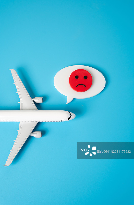 蓝色背景上的玩具飞机和伤心表情符号图片素材