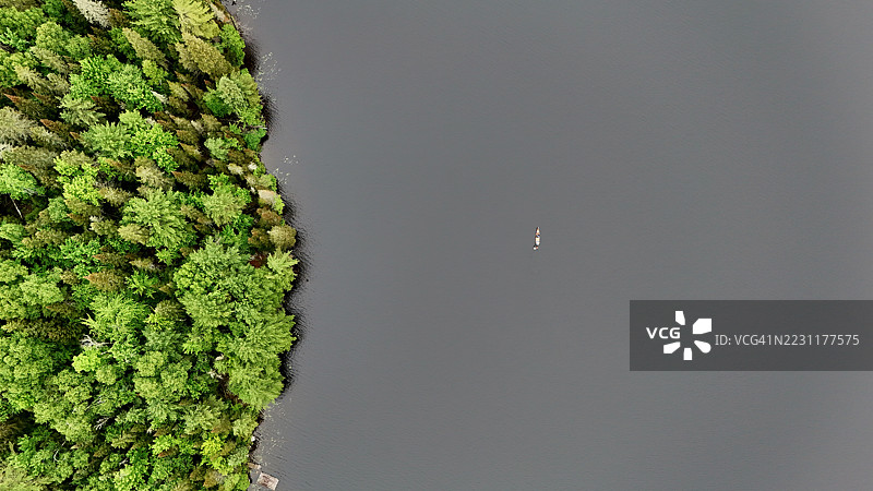 宁静湖泊中孤独浮标的鸟瞰图，四周环绕着郁郁葱葱的森林图片素材