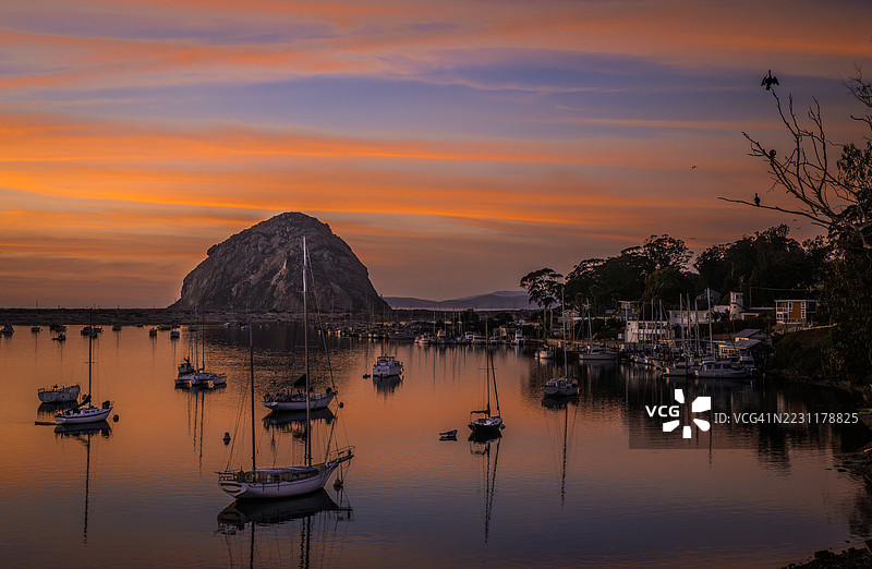 日落时分，停靠在宁静海湾的船只，背景是岩石山丘，莫罗湾，美国图片素材