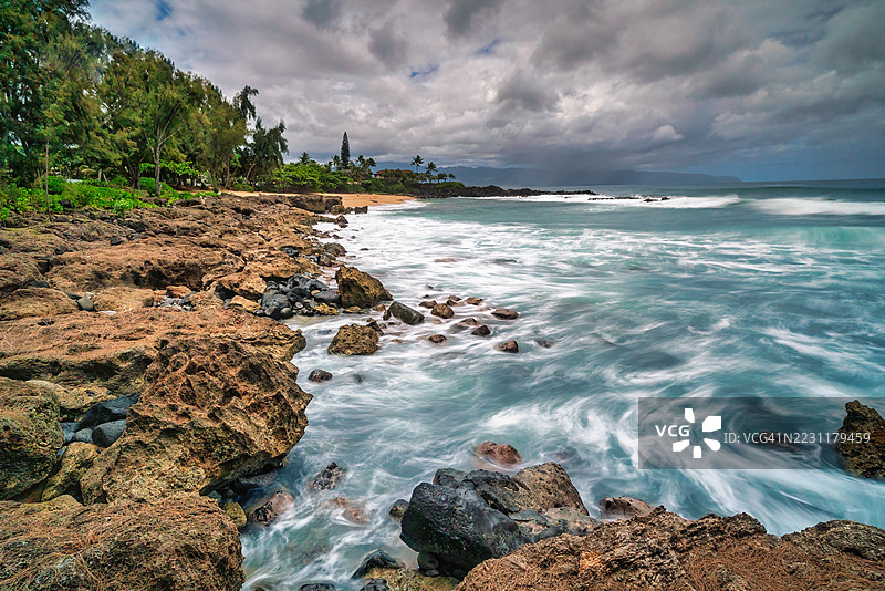 多云天空下波涛汹涌的岩石海岸线图片素材