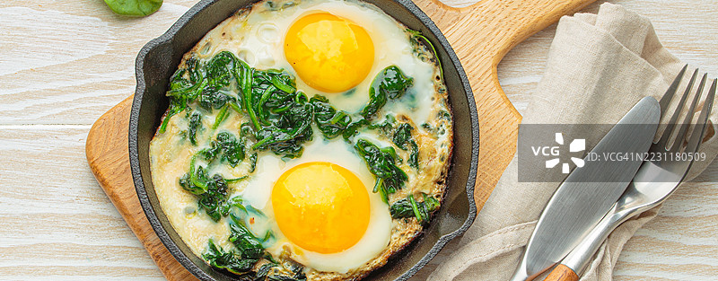 铁锅煎菠菜鸡蛋放在木桌上图片素材