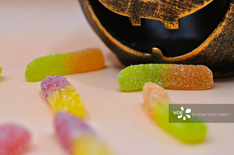 五彩缤纷的软糖虫从万圣节南瓜容器中倾泻而出图片素材