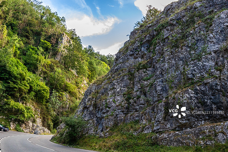 穿过岩石峡谷和郁郁葱葱森林的风景道路，切达，英国图片素材