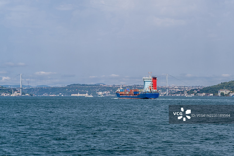 货船在博斯普鲁斯海峡航行，背景是城市风景和桥梁。图片素材