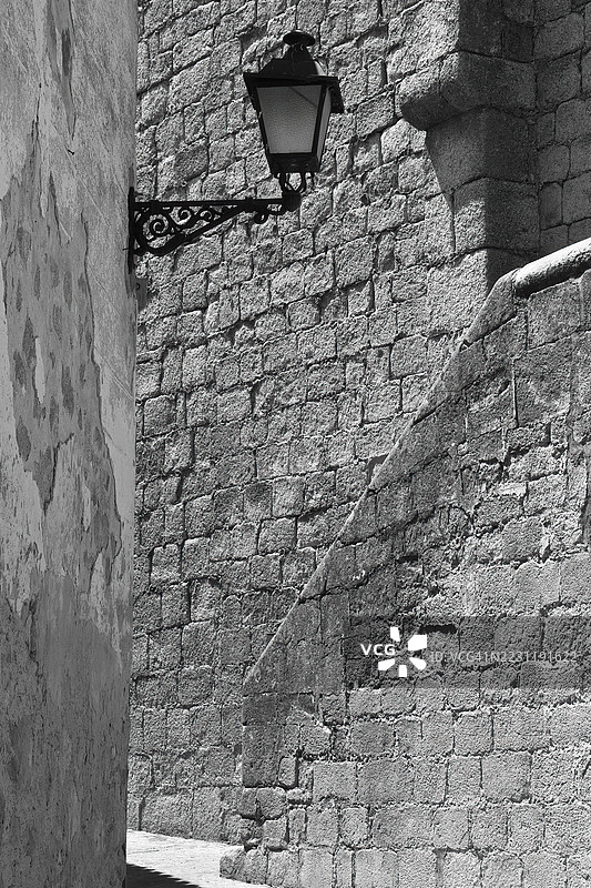 西班牙特鲁希略的石墙与复古街灯的黑白图像图片素材