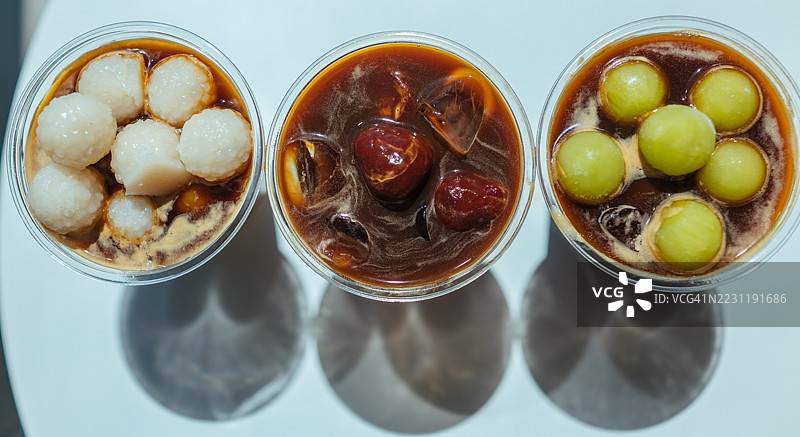 三杯带有水果配料的亚洲甜品饮料放在桌子上图片素材