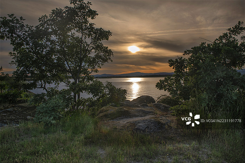 葡萄牙卡斯特洛布兰科宁静海面上的日落与剪影树木图片素材