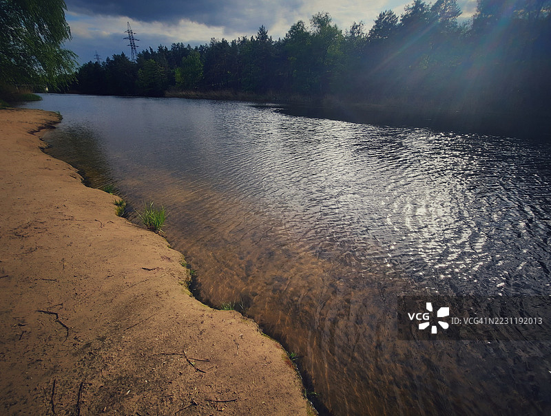 宁静的湖泊被森林环绕，天空多云图片素材