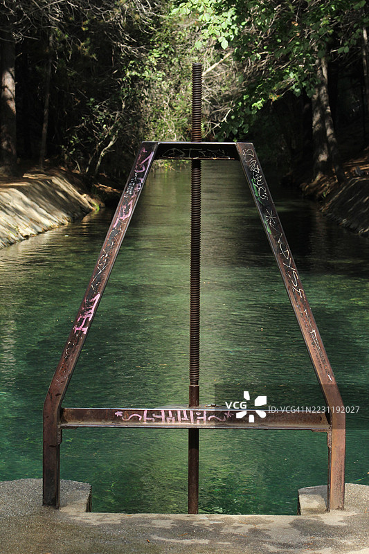 涂鸦覆盖的金属结构，横跨宁静的森林河流图片素材