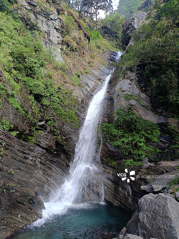 壮丽的瀑布倾泻而下，穿过郁郁葱葱的森林图片素材