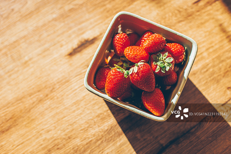 新鲜草莓放在木桌上的碗里图片素材