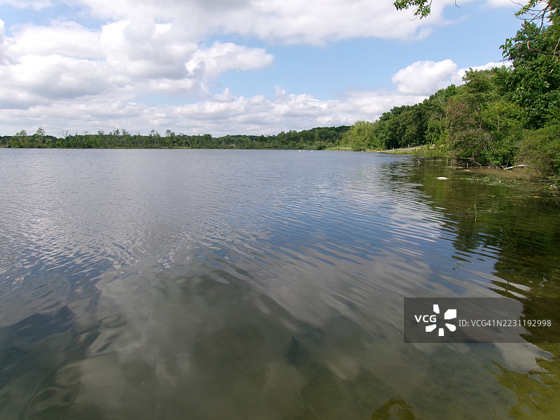 宁静的湖泊与森林环绕的岸边在多云的天空下，维克斯堡，美国图片素材