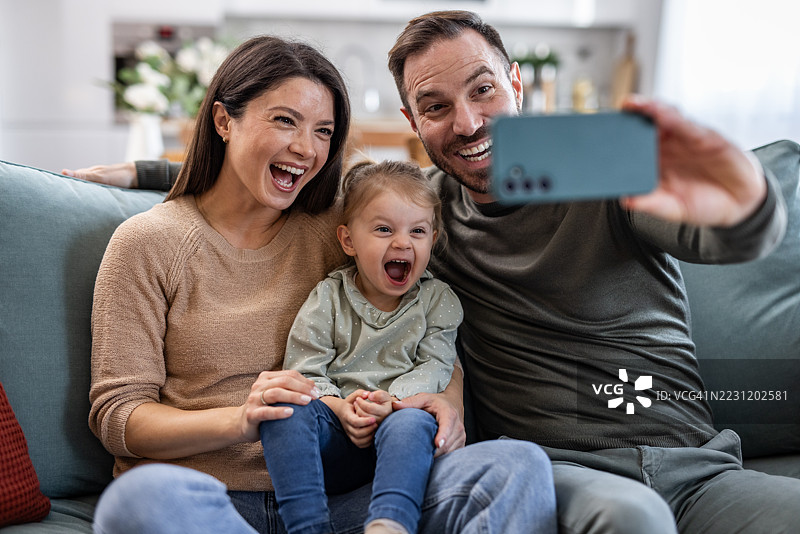 快乐的家庭在家里的沙发上自拍图片素材