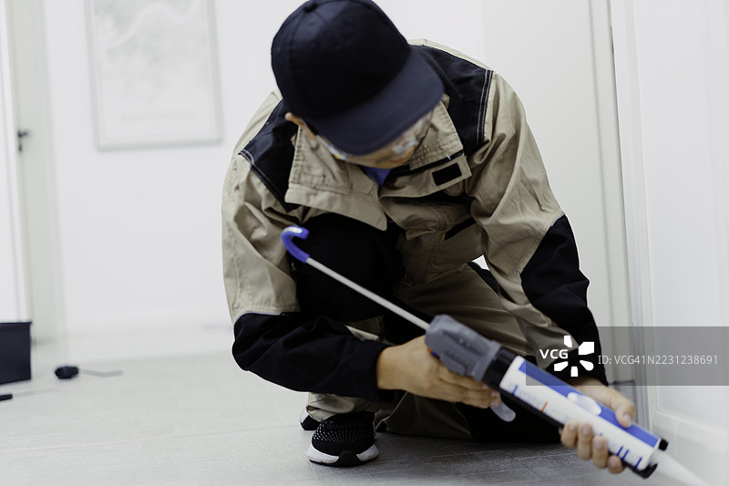 一名男性工人在家中安装PVC地板图片素材