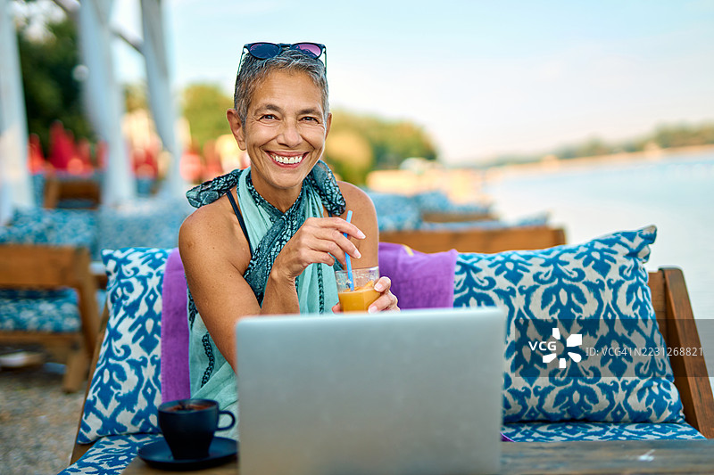 一位资深自由职业女性在度假时享受果汁图片素材