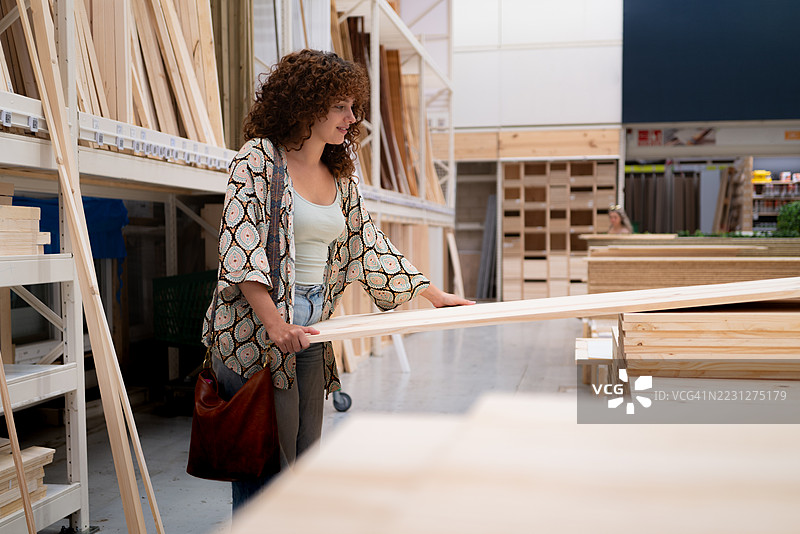 年轻女性在设备齐全的DIY商店挑选木材图片素材