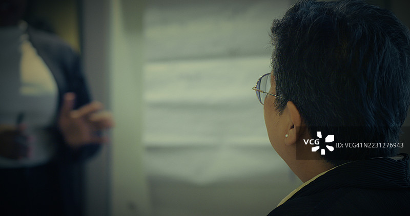 成熟的女商人在公司会议中专注地倾听演讲，体现了领导力、积极倾听、专业沟通和职场合作。图片素材