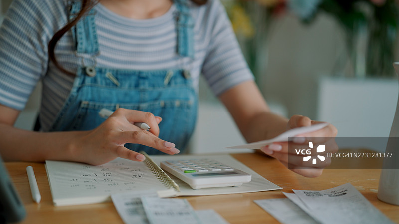 女性在为她的花店整理账单，同时计算收入和支出。图片素材