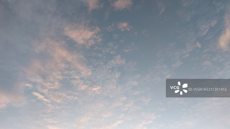 柔和的粉彩云朵在日落时分映衬着蓝天图片素材