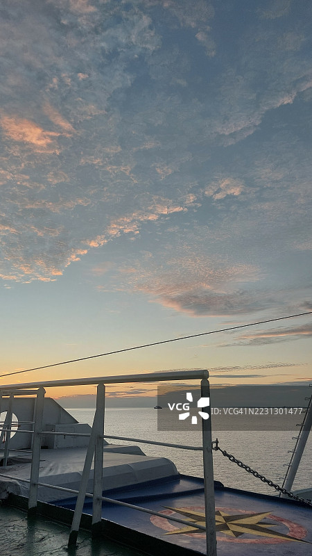 黄昏时分，从渡轮甲板上俯瞰柔和色调的日落天空与宁静的海洋地平线。图片素材