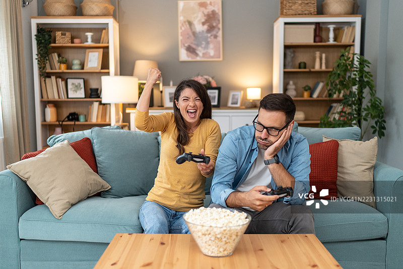 兴奋的女性在电子游戏中战胜无聊的男性图片素材
