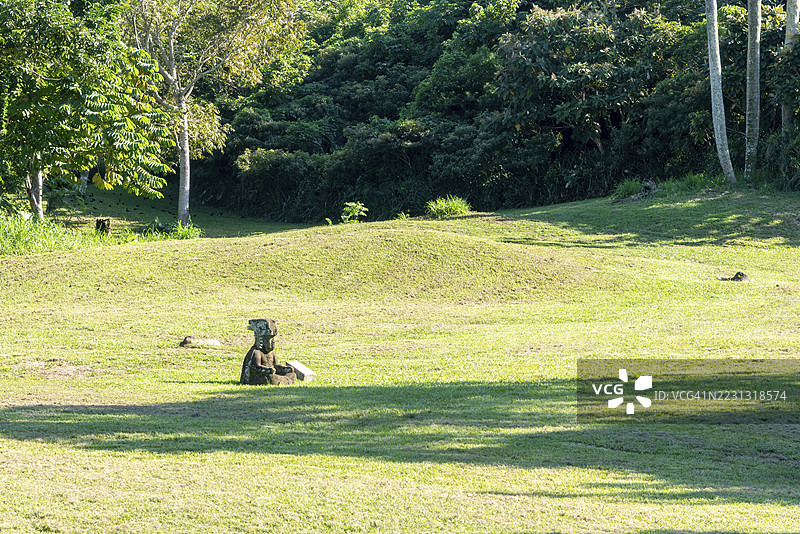 奥尔梅克时期的小雕像，位于开阔的绿地中，四周环绕着树木和阴影，地点为墨西哥塔巴斯科州莱瓦塔图片素材