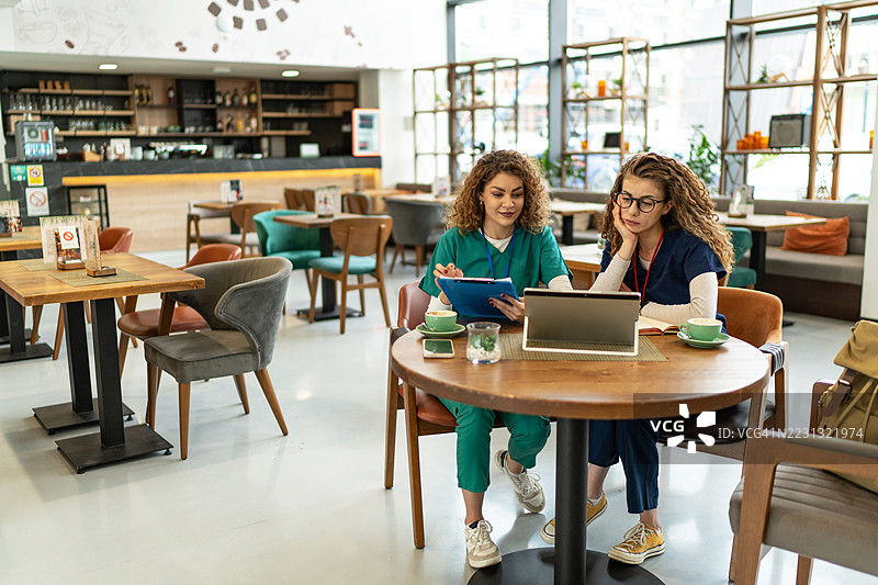 两名年轻护士在咖啡休息时间讨论医疗信息图片素材