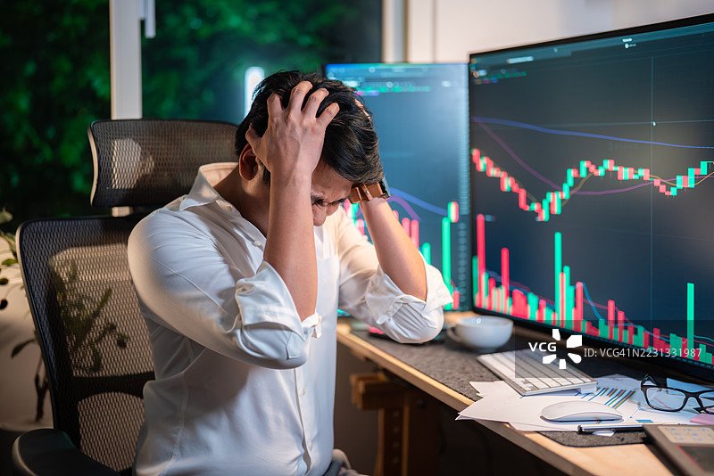 压力山大的男人在观看市场崩溃时抓着头部图片素材