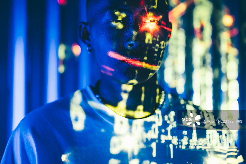 一个人的脸被投射的数字代码以及充满活力的蓝红色灯光照亮，一只眼睛上有一个明亮的红色投影。这幅霓虹肖像涵盖了人工智能、未来科技和数字身份等主题。图片素材