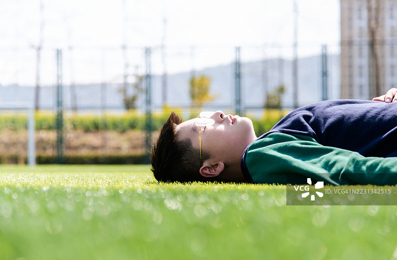 公园里躺在草地上的少年图片素材