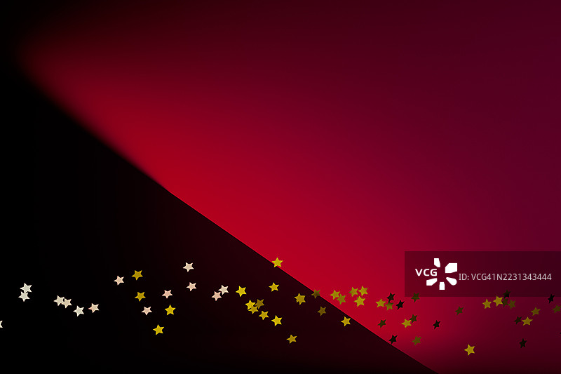 红黑渐变背景上的金色星星彩纸屑图片素材