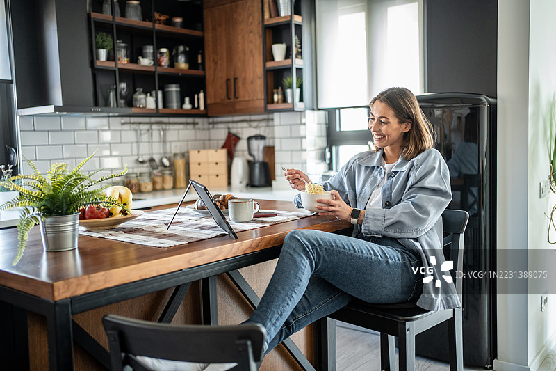女性在现代厨房中享受早餐和在线内容图片素材