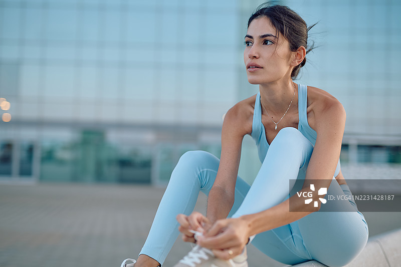 年轻女运动员在户外训练前系鞋带图片素材