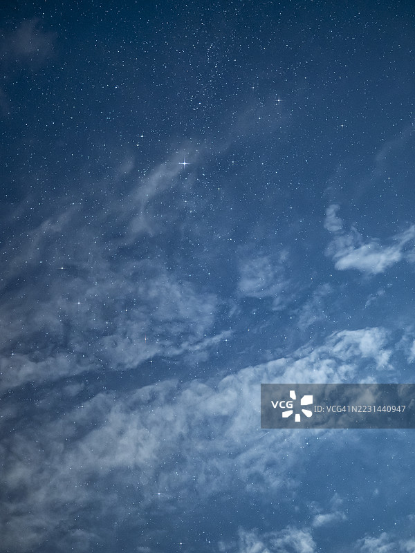 夜空中闪烁着明亮的星星，薄薄的云层覆盖着，正值满月之夜。图片素材