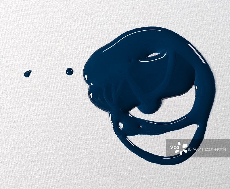 蓝色指甲油液体污渍滑落在白色背景上。图片素材