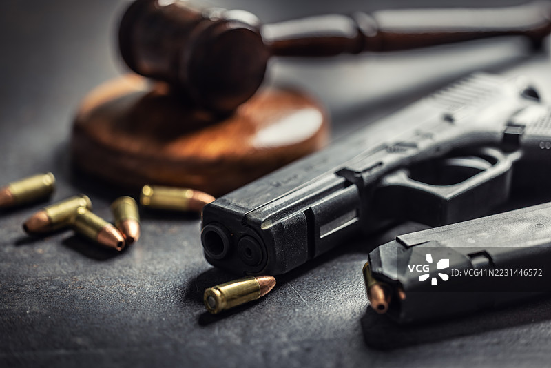 象征持有武器权利的手枪与子弹，背景中有法官的法槌。图片素材