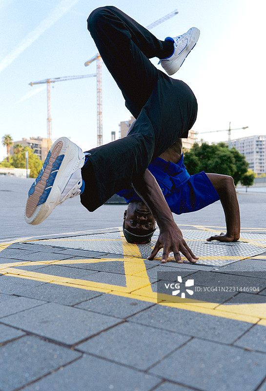 城市街头舞者表演重力反转动作，强劲的运动街舞技巧使身体倒立。图片素材