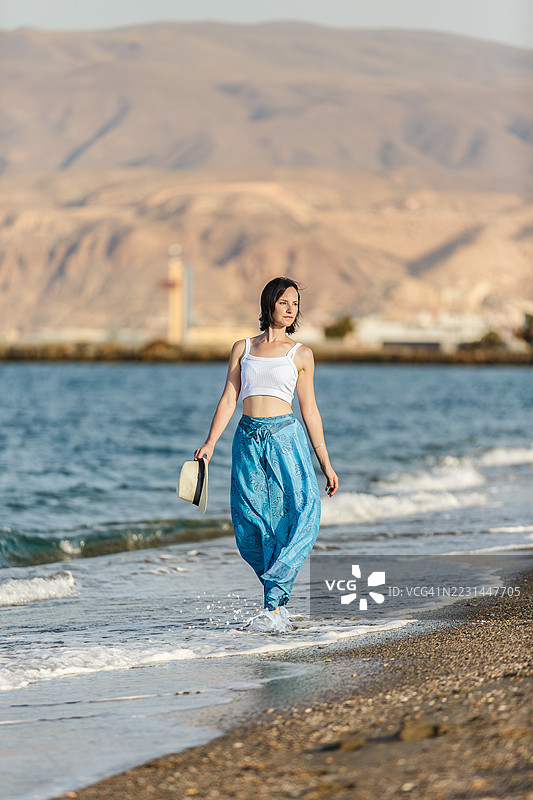 年轻女性在西班牙阿尔梅里亚的海滩上散步图片素材
