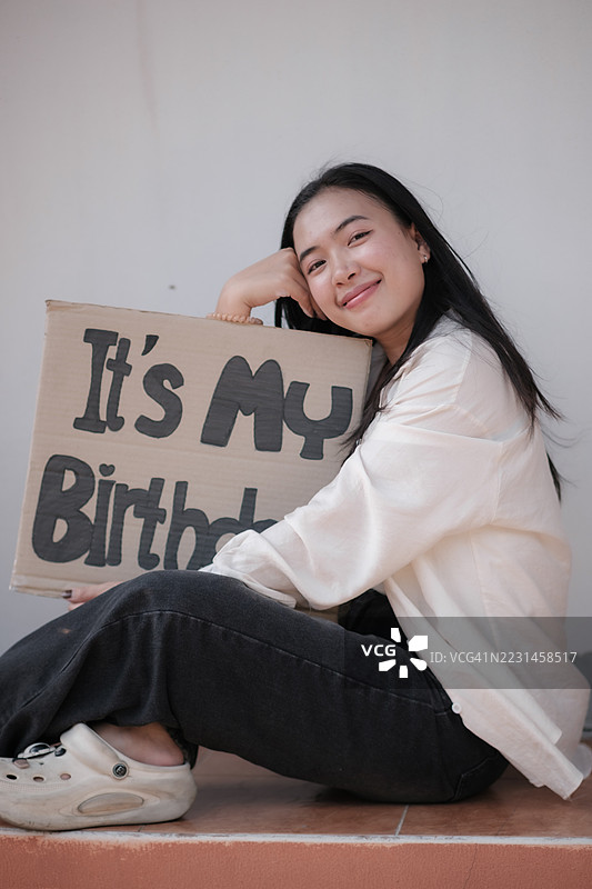 一位亚洲女性在生日当天手持“我的生日”标志。图片素材