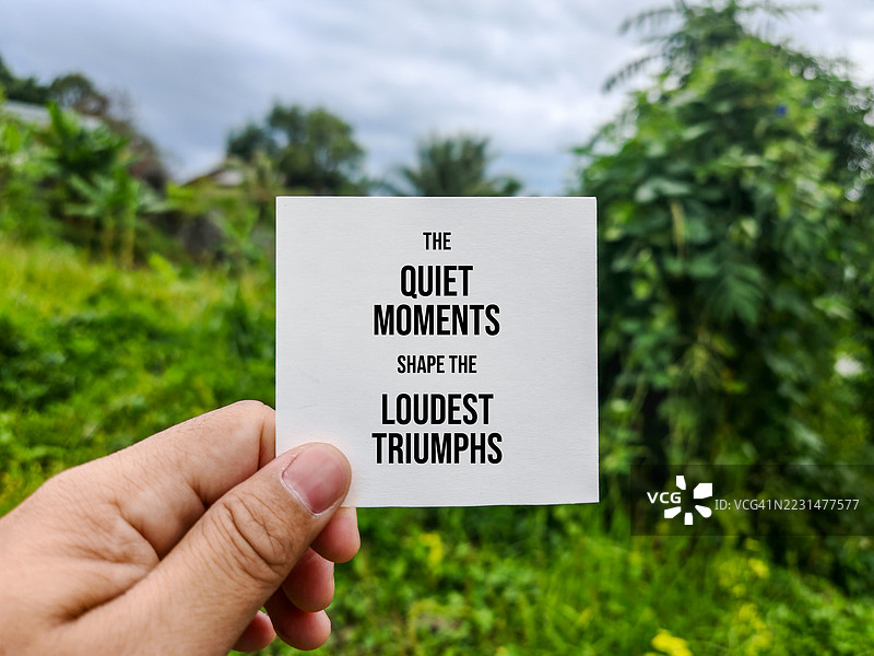 手握励志名言卡片置于自然中图片素材