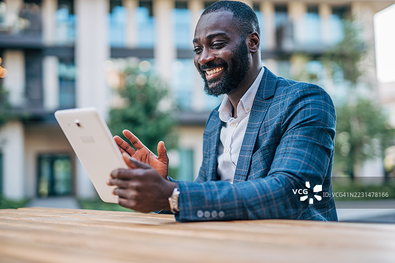 微笑的商人在户外用平板电脑视频通话图片素材