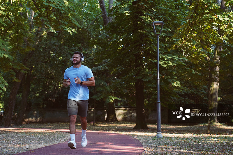 年轻男子在公园慢跑——户外健身与健康生活方式图片素材