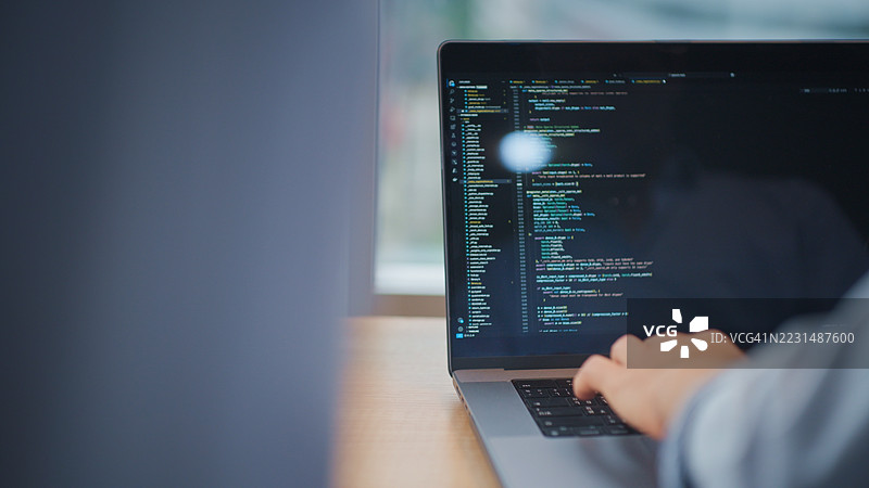 软件开发人员在现代办公室的协作会议中，近距离查看笔记本电脑上的代码。图片素材