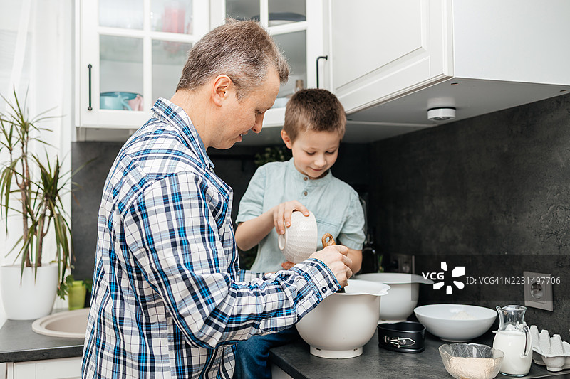 父亲和儿子在搅拌碗里准备食材，一起烘焙图片素材