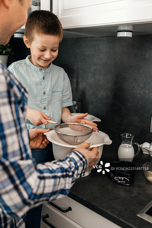 父亲和儿子在厨房一起筛面粉图片素材