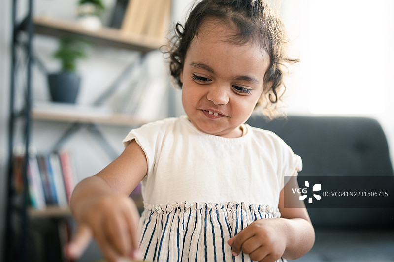 小女孩在家里玩玩具：专注的表情图片素材