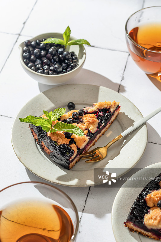 阳光明媚的桌子上的蓝莓挞和茶图片素材