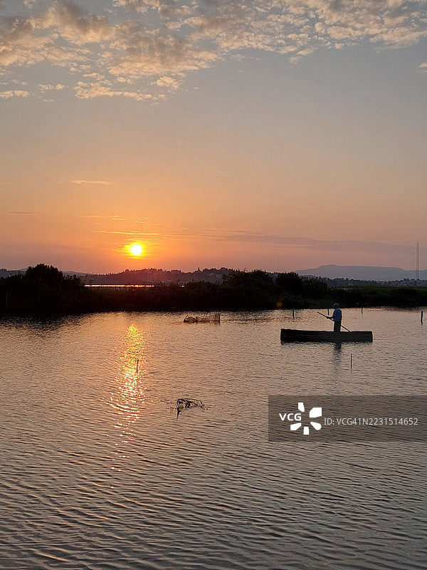 宁静的湖面日落与孤独的划船者图片素材