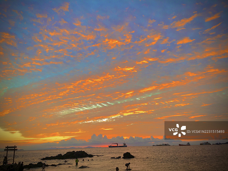 印尼索龙市海上绚丽的日落，剪影中的人们和船只图片素材
