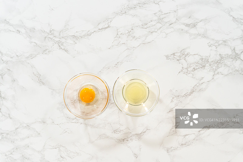 大理石表面上玻璃碗中分开的蛋黄和蛋白的俯视图图片素材